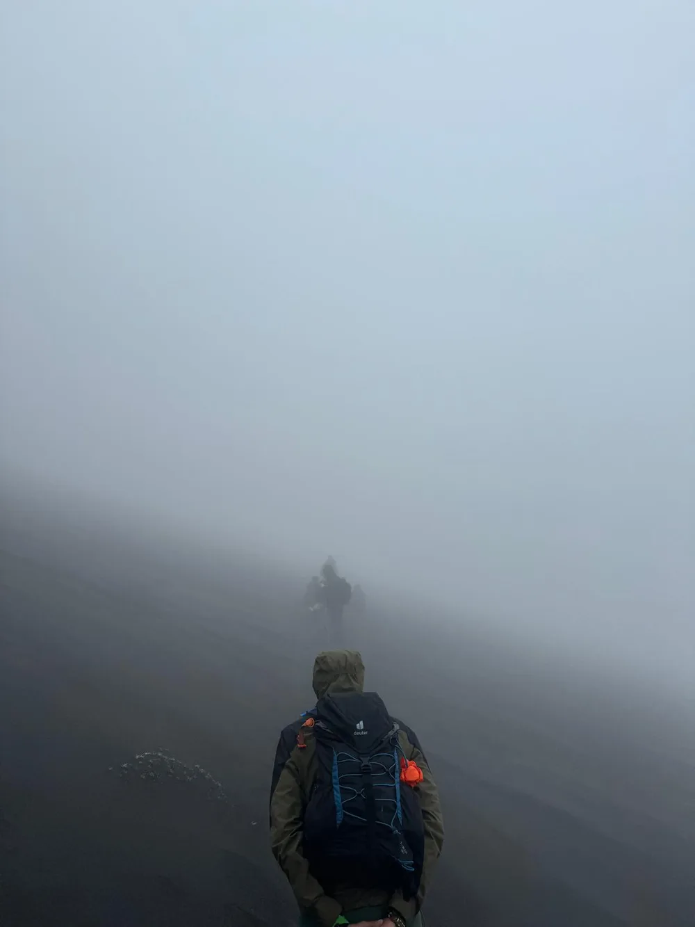 Hikers following one another into dense fog on Mount Etna.