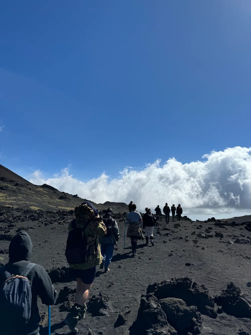 The Cogram team hiking across volcanic terrain above the clouds.